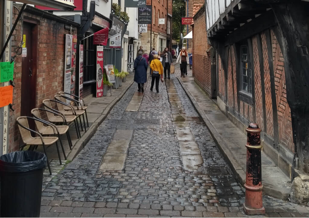 A narrow, cobbled alleyway in York, lined with various shops and historic buildings.